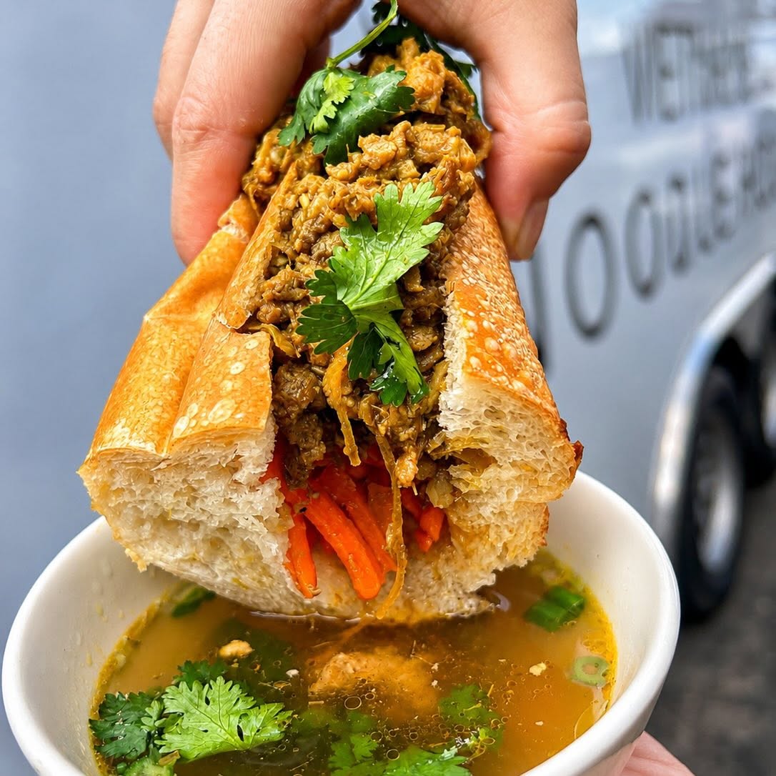 Banh mi dipped into a bowl of broth